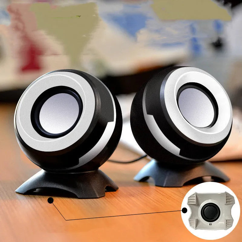 Compact black and gold USB-powered stereo computer speakers beside laptop