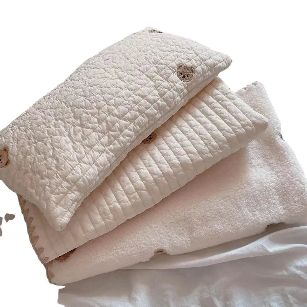 Simple bear print square dog bed set with pillow, mattress, and quilt on a floor.