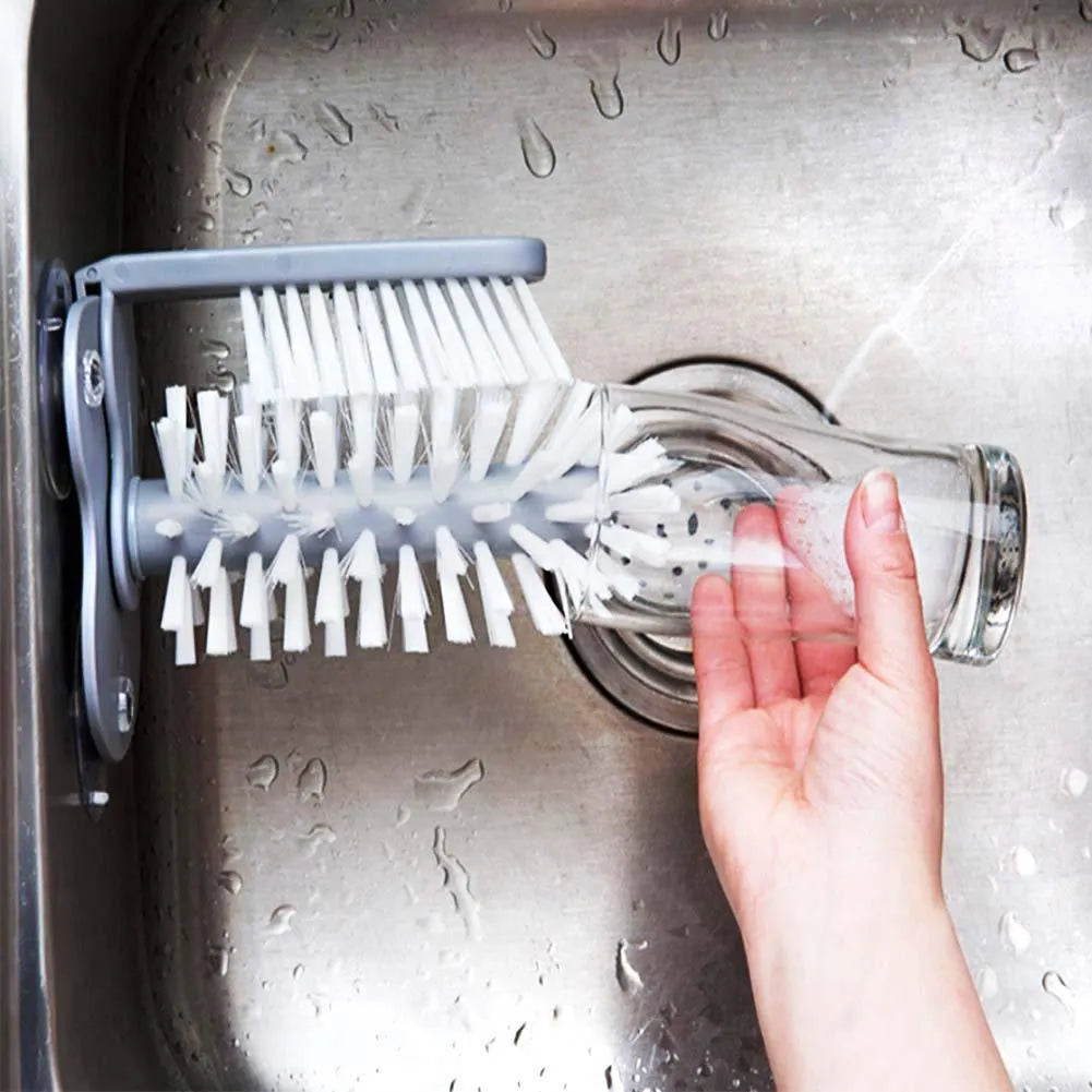 Grey 2-in-1 cup scrubber with double-sided bristles and three suction cups on a white surface