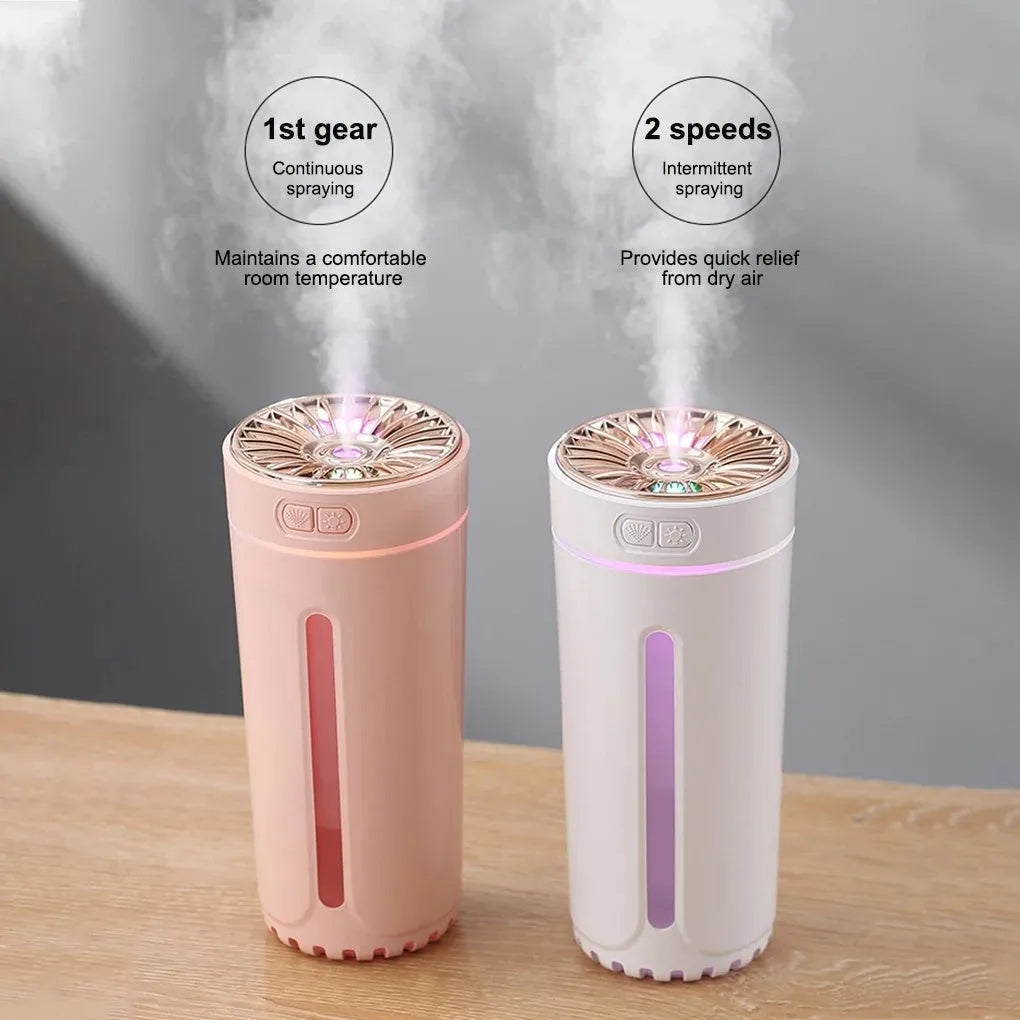 Black and white portable USB rechargeable car humidifier with colourful LED lights on a desk.