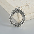 A pair of large antique silver hoop earrings with a hollow-out geometric dragon shape design.