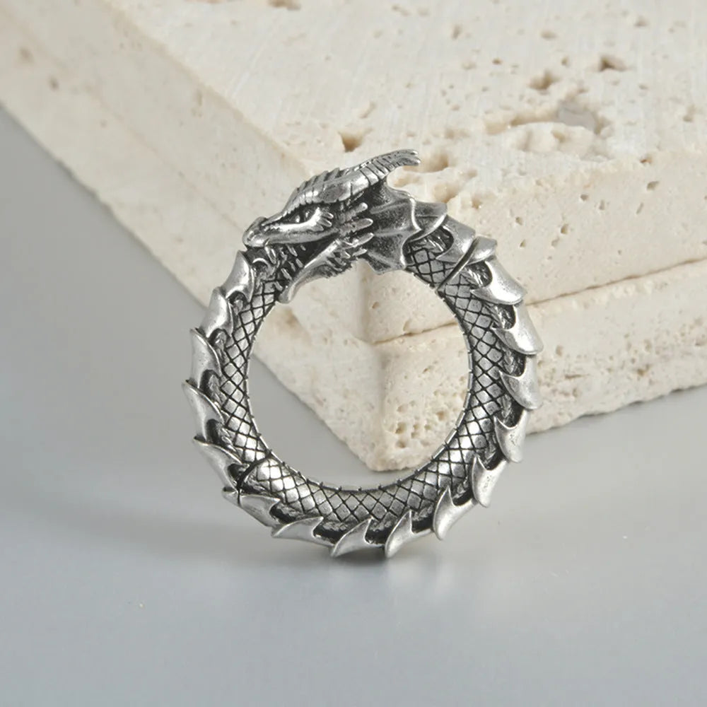 A pair of large antique silver hoop earrings with a hollow-out geometric dragon shape design.