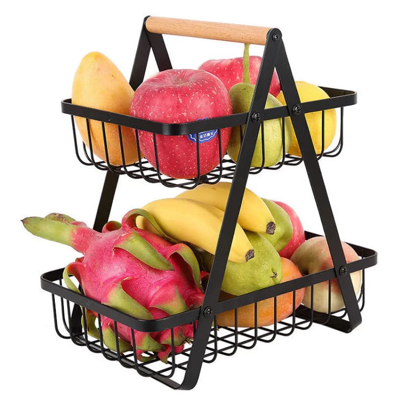 Black detachable iron double-layer fruit basket with a wooden handle on a kitchen counter.