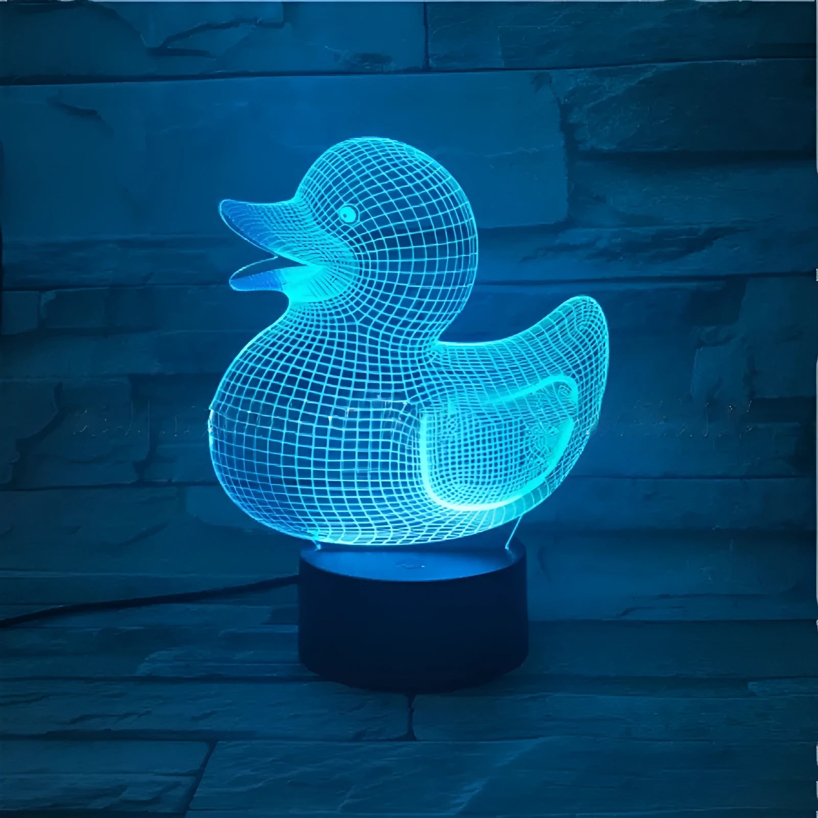 Little yellow duck 3D night light with remote control on a table, showing its colourful LED illumination.