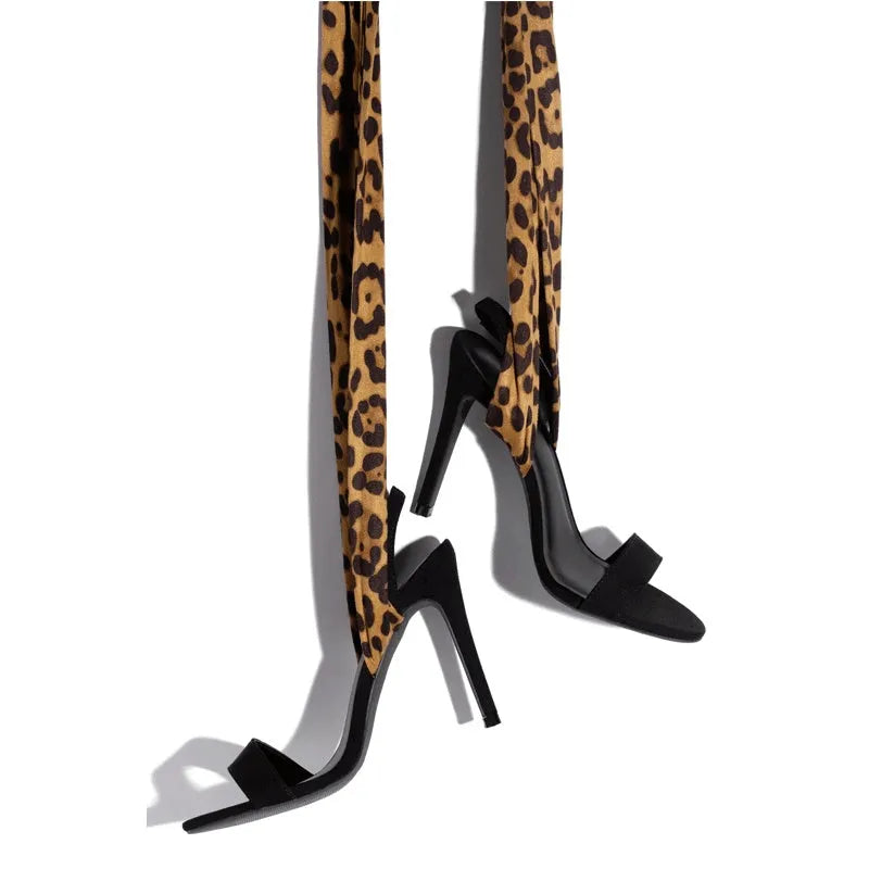 Light brown leopard print women's high-heeled sandals with cross-straps and a tall slender heel.