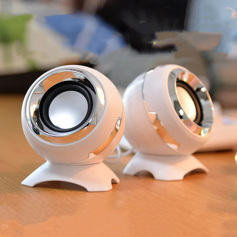 Compact black and gold USB-powered stereo computer speakers beside laptop