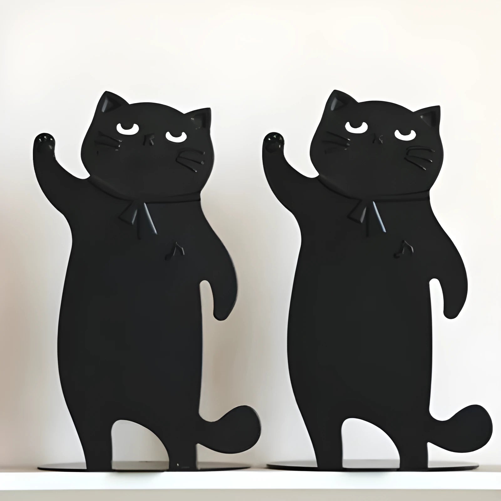 Set of two cartoon cat music themed iron bookends in black and white on a desk holding books upright