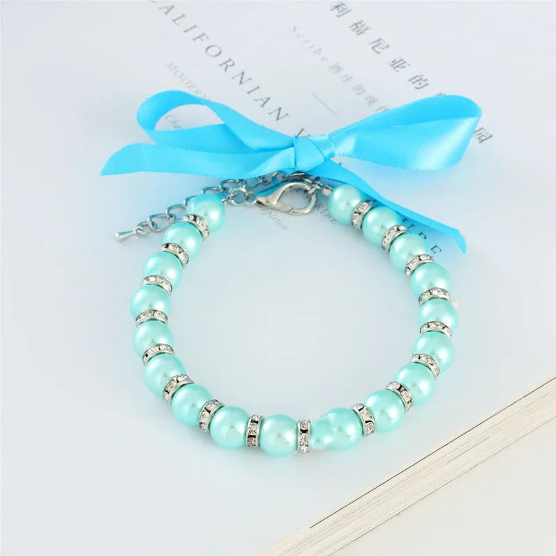Small dog wearing blue imitation pearl necklace with rhinestones and ribbon bow adjustable collar