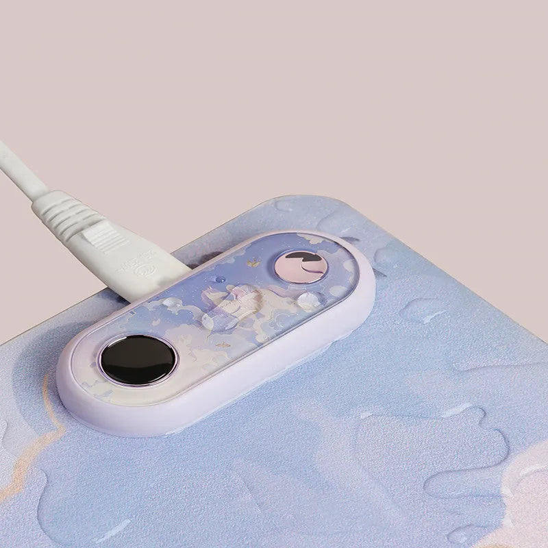 USB desktop heating pad on a desk, showing the fish leaping design on a grey PVC leather surface measuring 30 by 15 cm.