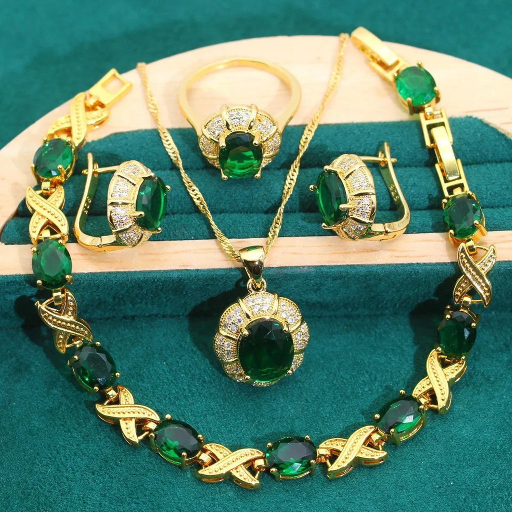 Gold plated necklace, earrings, ring, and bracelet set with blue cubic zirconia stones on a grey background.