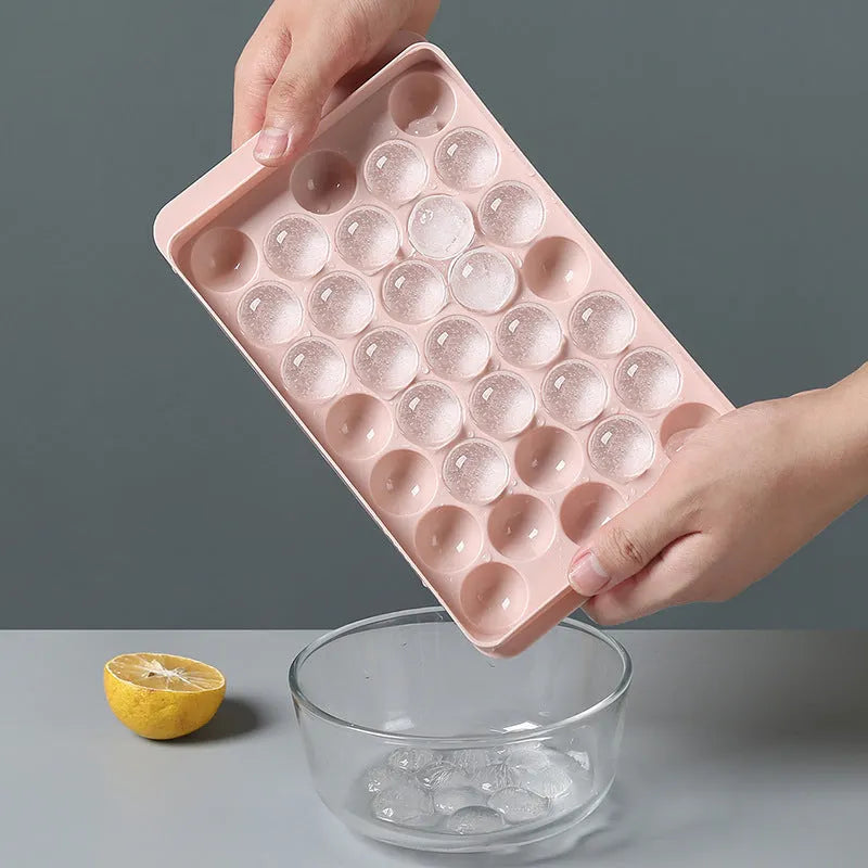Sky blue and pink 3D round ice cube mould trays showing spherical cavities.