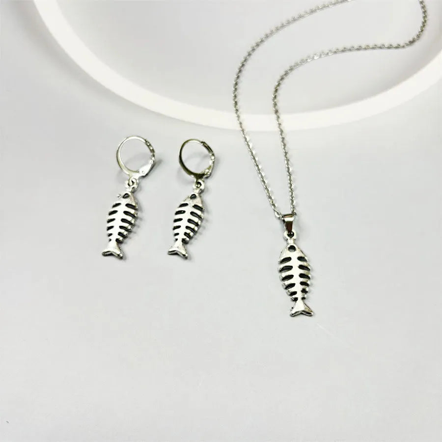 Women's fishbone pendant necklace and matching earrings set with adjustable chain on retro background