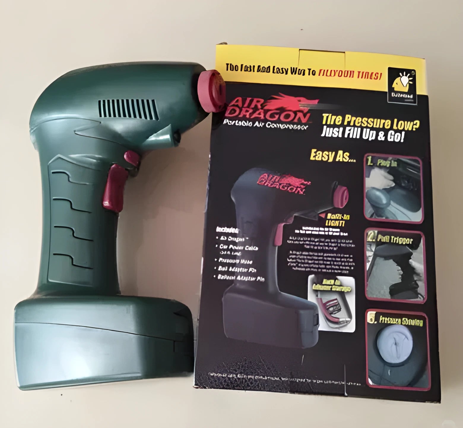 Compact black 12V portable car tyre pump with digital display, LED light, hose, and valve adapters on a grey background.