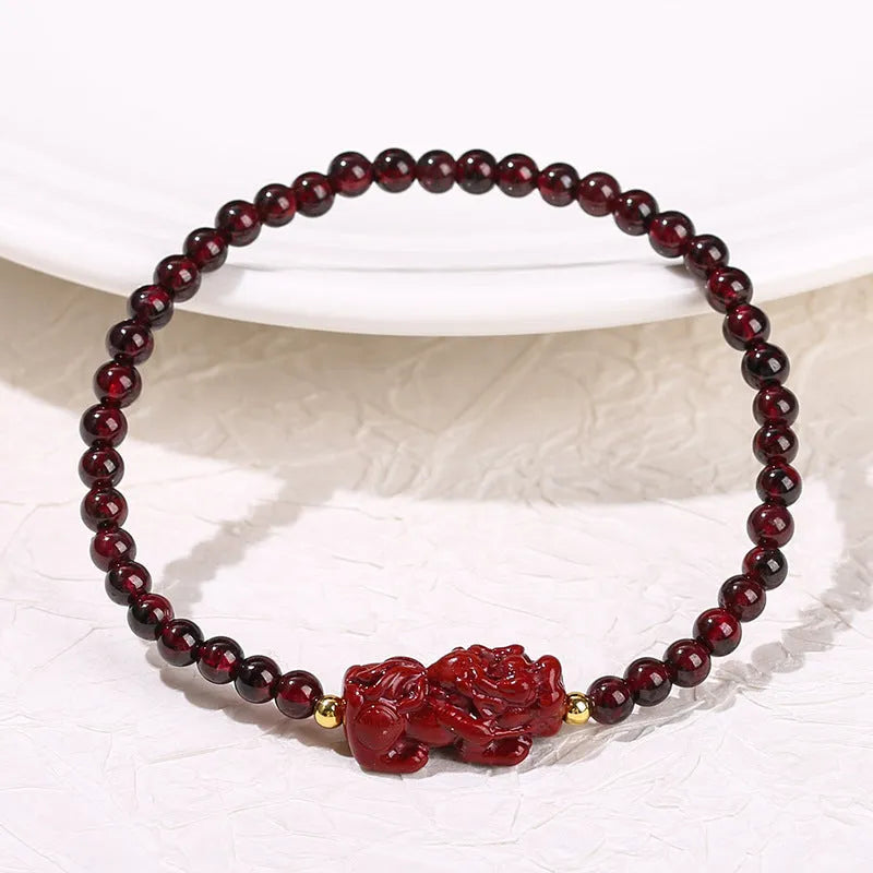 Geometric square garnet bracelet with carved Pixiu and strawberry quartz accents on a purple sand background.