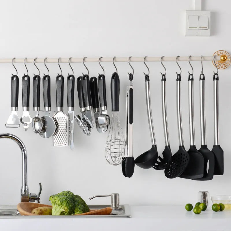 Black silicone kitchen utensil set with stainless steel handles showing various spatulas and spoons