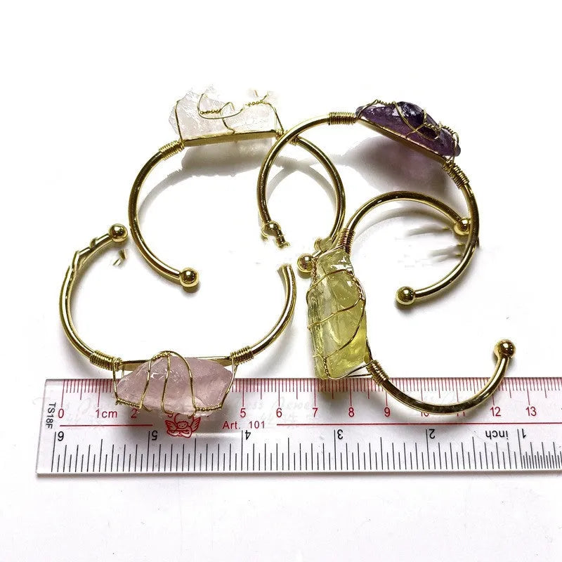 Natural rough stone crystal bracelet with gold geometric winding on a wrist.