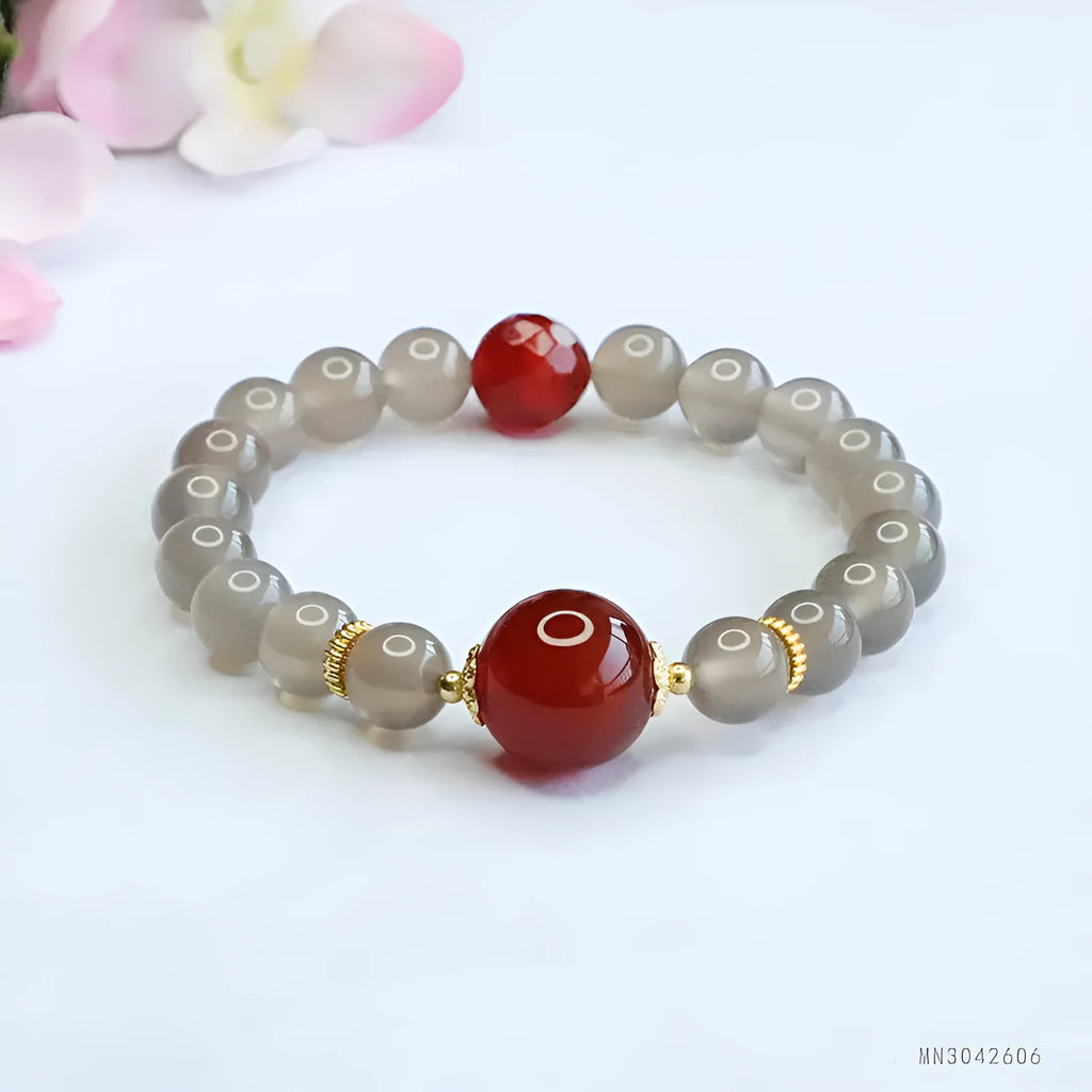 Close-up of a bracelet with smoky purple and red agate geometric beads on a white background.