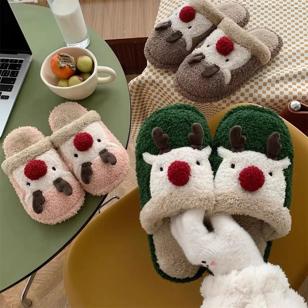 Women's brown Christmas elk plush slippers with non-slip PVC sole on a wooden floor.