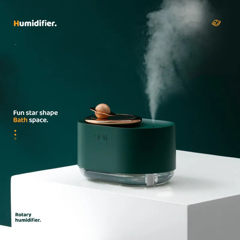 Green rotating planet USB humidifier with night light on a desk next to a laptop.