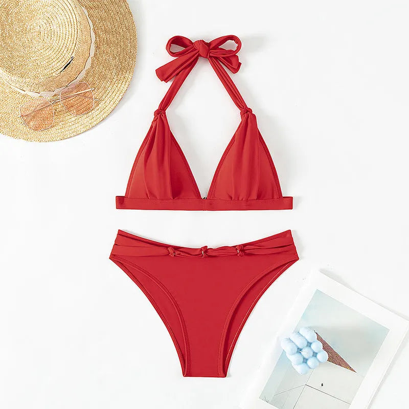 Red women's lace-up halterneck bikini with split shorts laid flat.