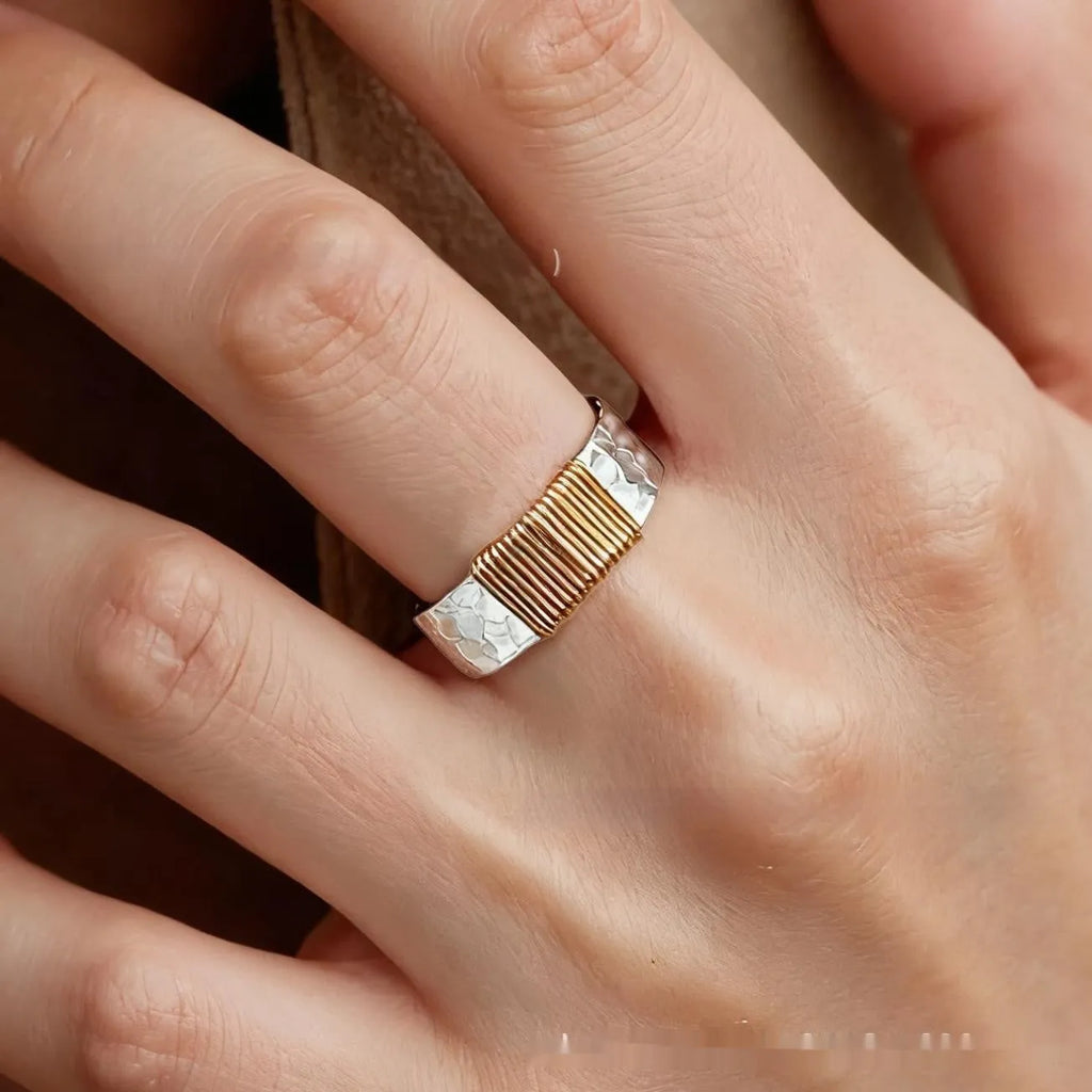Copper wide face geometric ring bracelet in silver gold coil colour on a plain background.