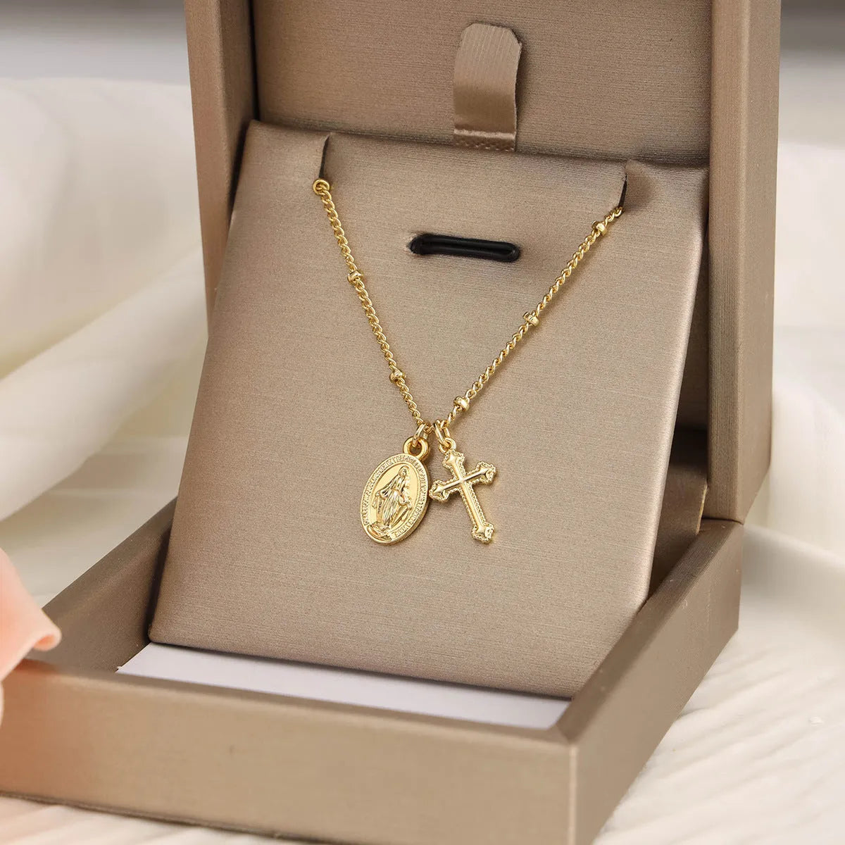 Geometric gold Virgin Mary cross pendant necklace on a chain.
