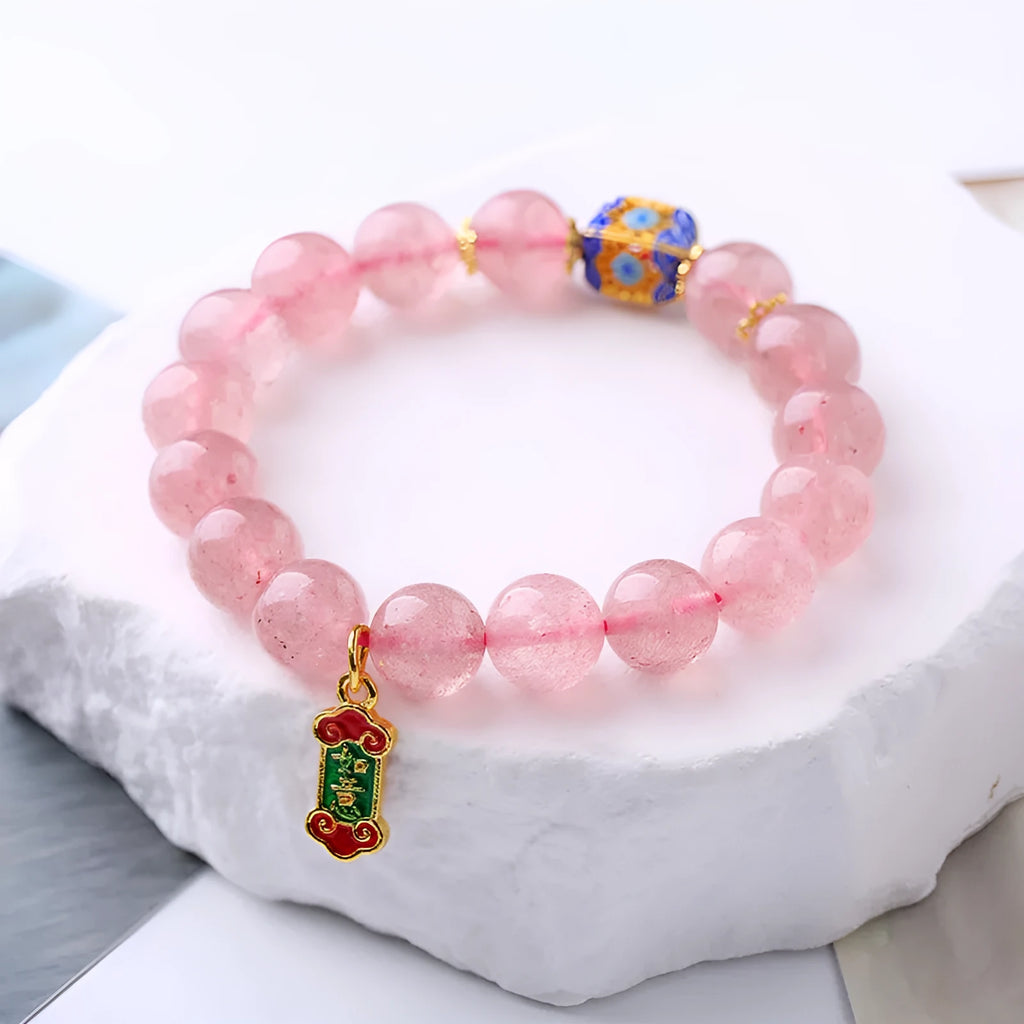 Pink strawberry quartz crystal bracelet with hand-woven beads, Ruyi charm, and letter charms.