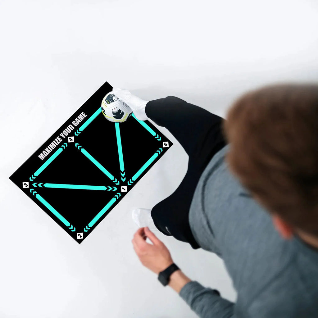Black rectangular football training mat measuring 60 by 90 cm on a grass surface.