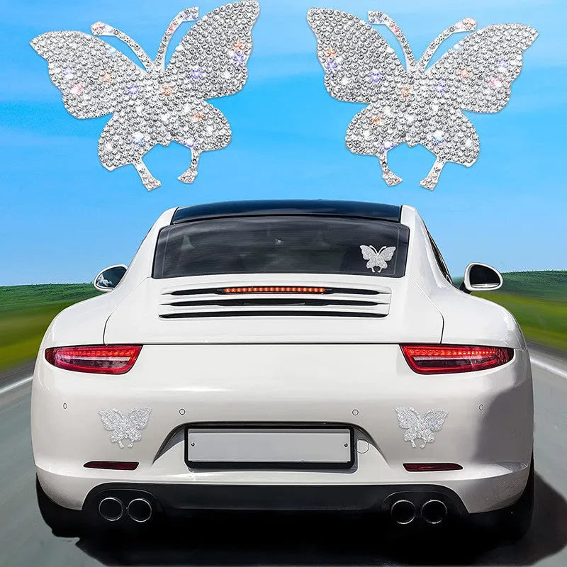 Close-up of a diamond-encrusted glass car sticker in butterfly and bear paw designs on a clear background.