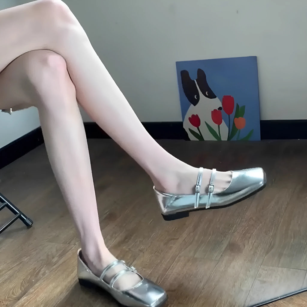 Women's silver leather Mary Jane flats with a cross buckle strap and round toe.