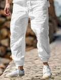 Men's straight-leg linen trousers in apricot colour with an elasticated waistband laid flat.