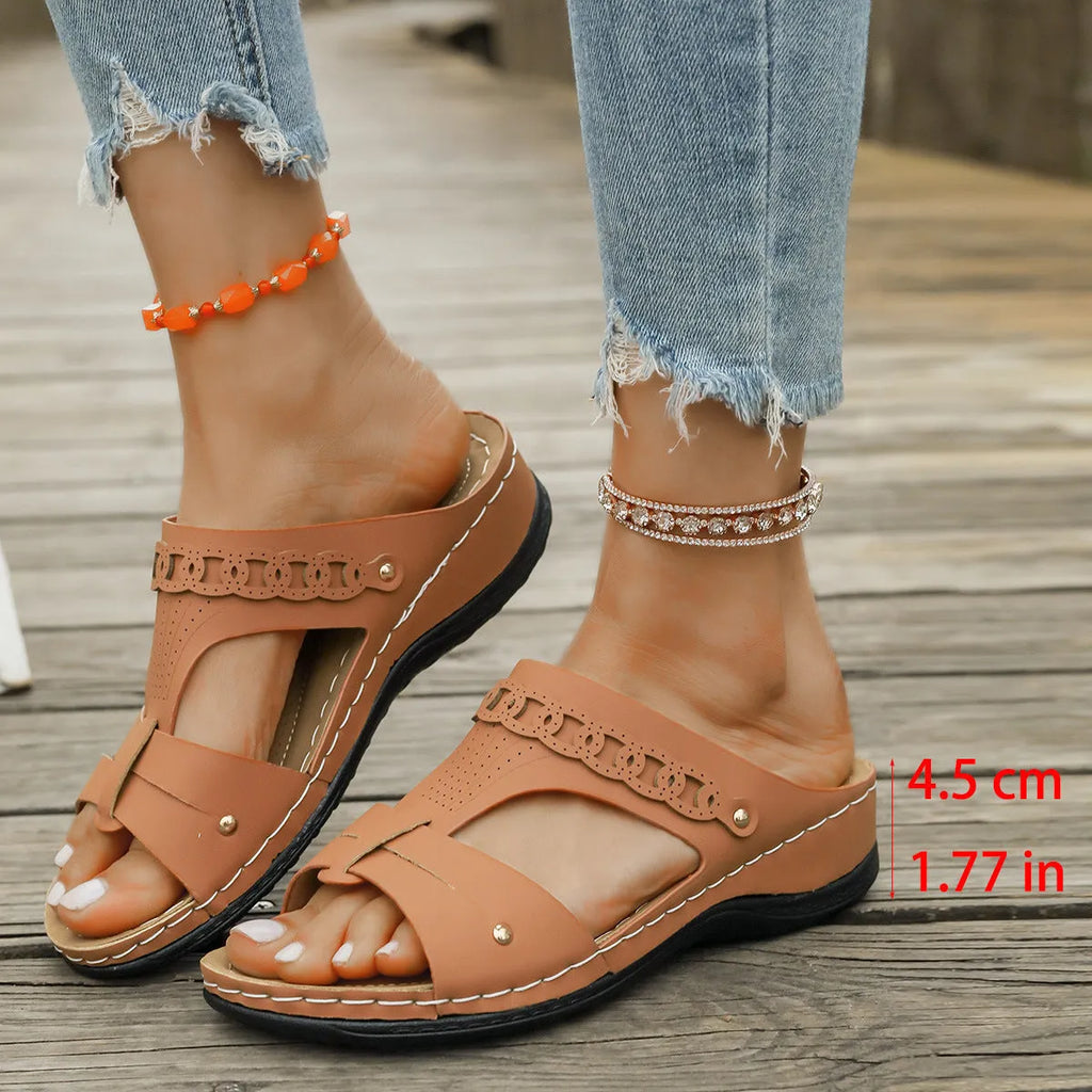 Women's blue Roman style slope heel slippers with fish mouth toe holder on a wooden floor.