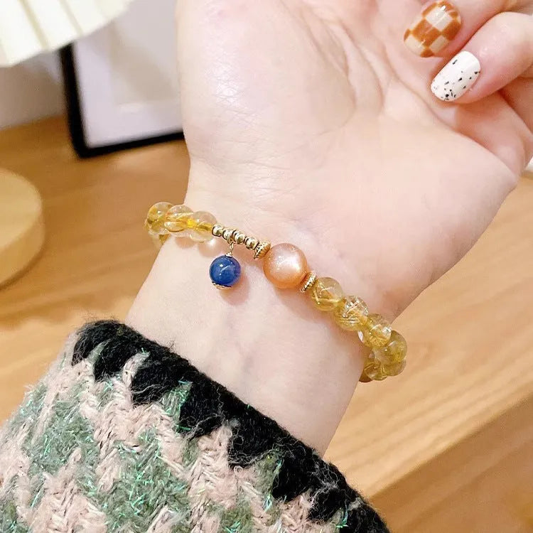 Gold rutilated quartz sunstone bracelet with diamond shapes and round beads on female wrist