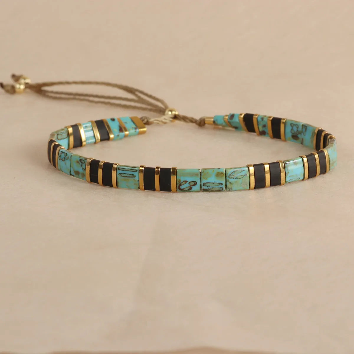 Geometric glass beaded bracelet in milky white, black, green, blue, or red on a plain background.