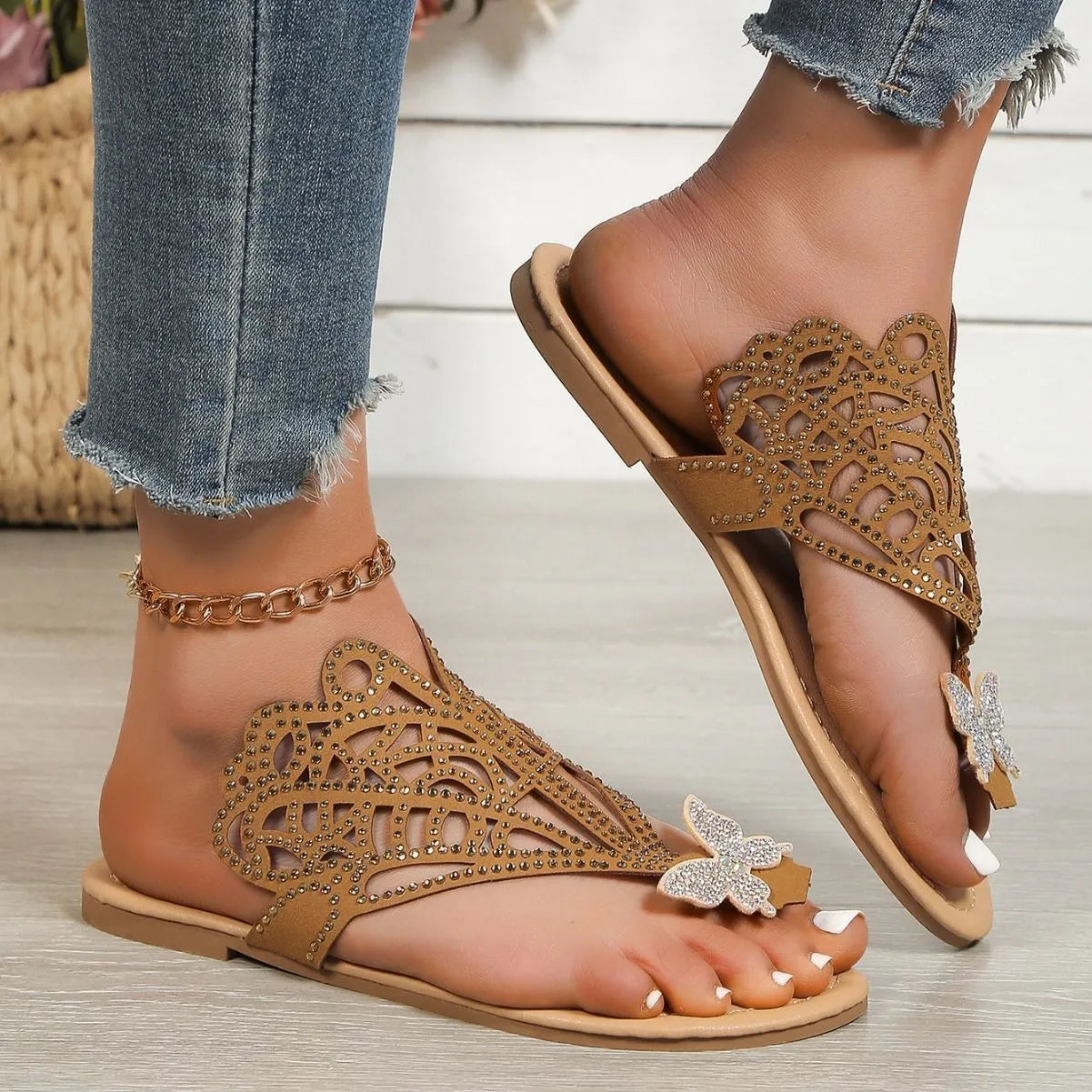 Women's black flip-toe sandals with rhinestone decorations and a hollow out design on a gold background.