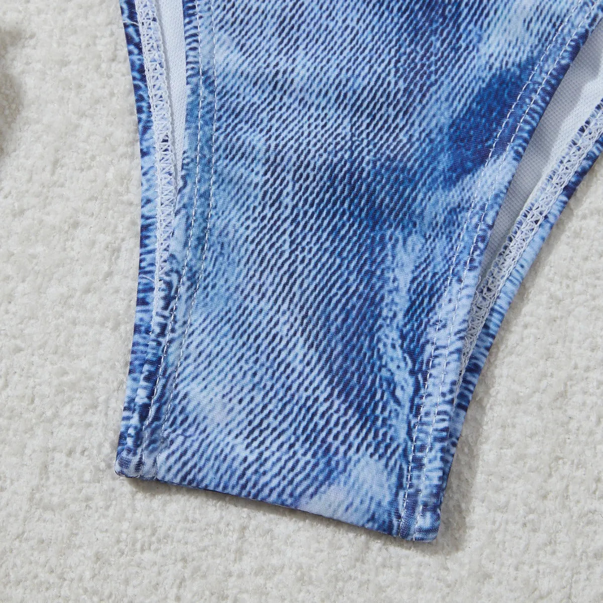 Denim blue printed women's bikini swimsuit with adjustable straps laid flat.