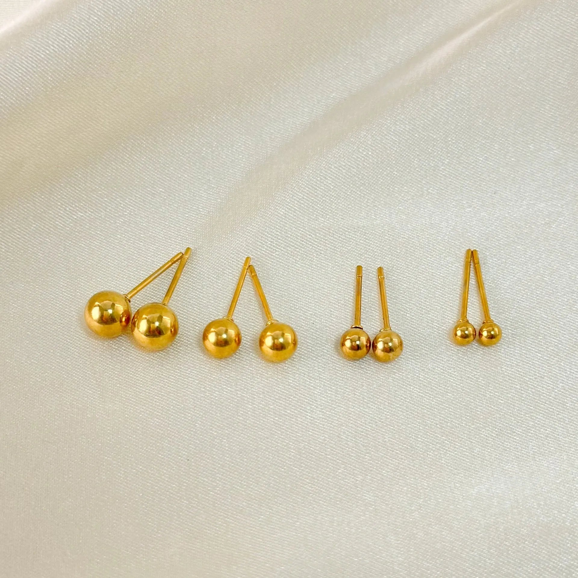 Stainless steel ball stud earrings in gold or silver finish, showing 3mm, 4mm, 5mm, and 6mm size options.