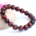 Red tigereye wood alexandrite bracelet with lightning cat's eye pattern on wrist.