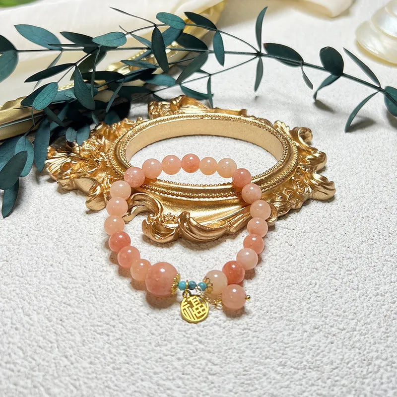 Close-up of a pink natural stone set within a simple silver-toned alloy women's bracelet.