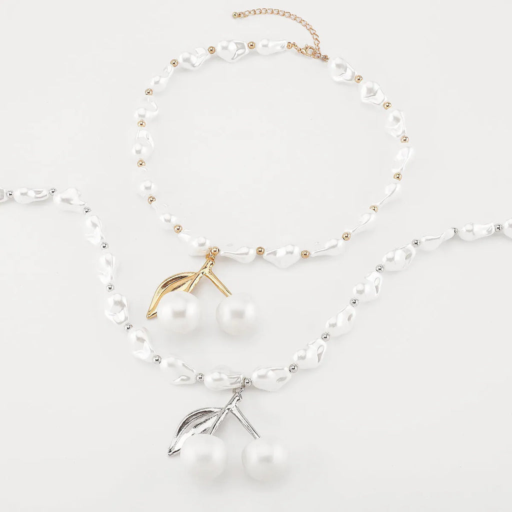 Gold-coloured adjustable necklace with a fruit-shaped pendant on a pearl-style chain.