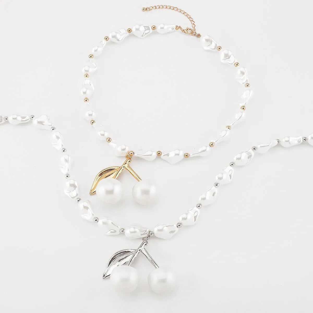 Gold-coloured adjustable necklace with a fruit-shaped pendant on a pearl-style chain.