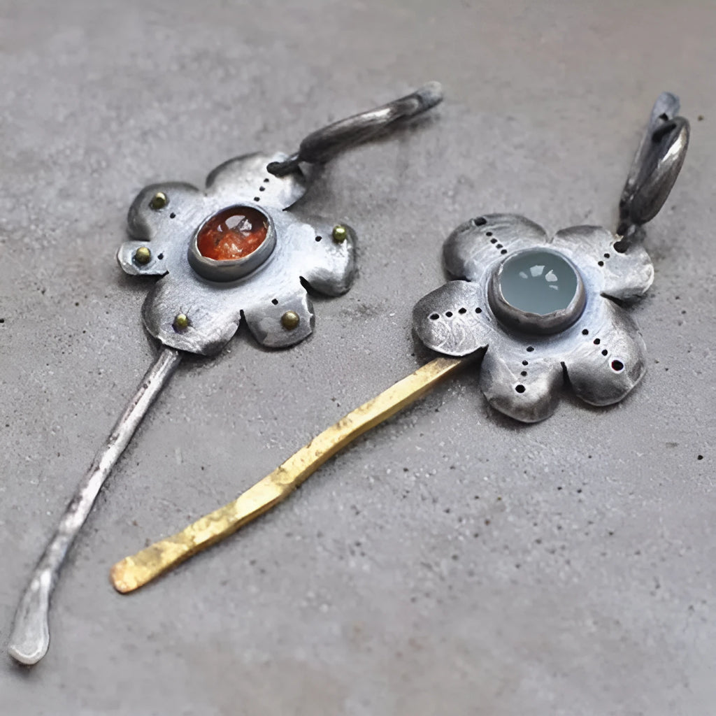 A pair of long, geometric flower-shaped retro earrings in two contrasting metallic colours with an asymmetrical design.