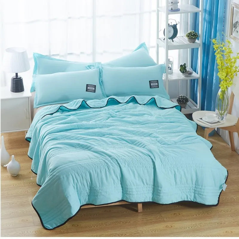 Plain colour seersucker summer cooling quilt shown in light pink on a bed.