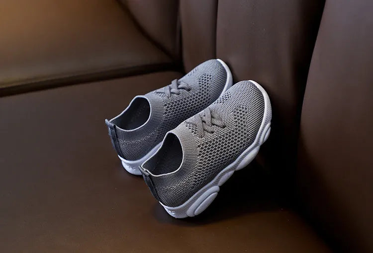 Children's lazy slip-on shoes in white, black, pink, or grey with fabric upper and rubber sole.