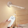 White LED cabinet night light unit with remote control on a table.
