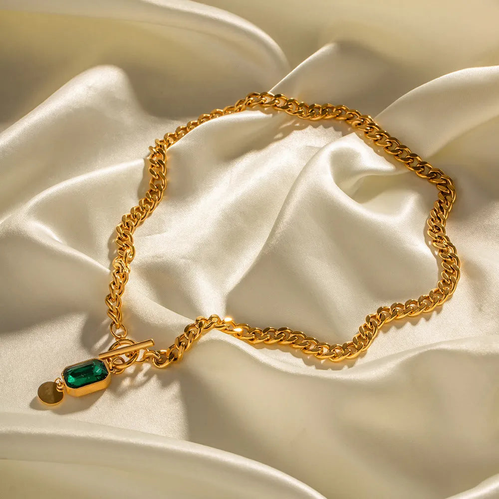 Gold titanium steel pendant necklace with geometric design and emerald zircon centre on Cuban link chain