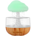 White cloud-shaped humidifier with multi-colour night light on a table.