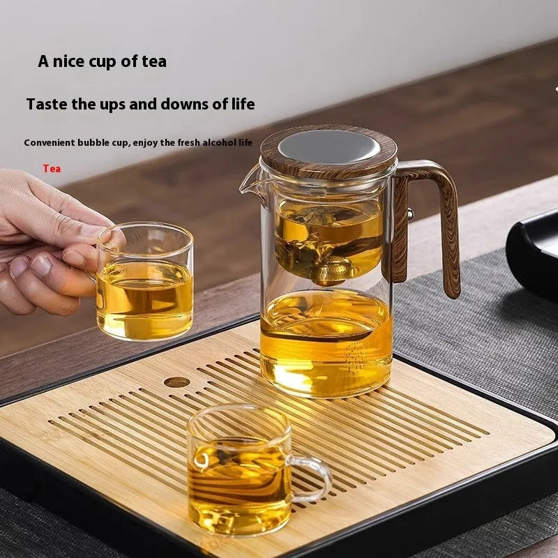 Glass teapot with wooden handle showing magnetic separation button and inner filter basket.