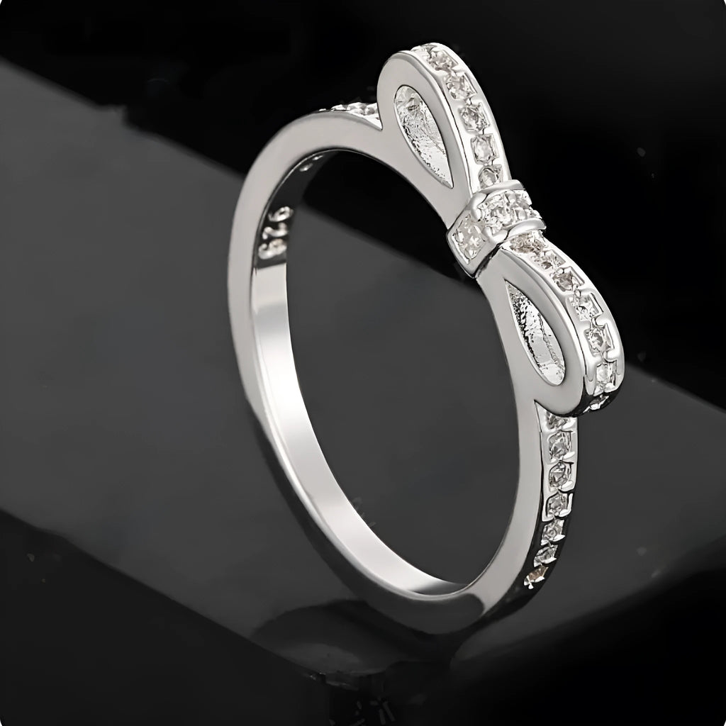 A silver couple-style ring with a bow shape decorated with rhinestones and zircon crystals.