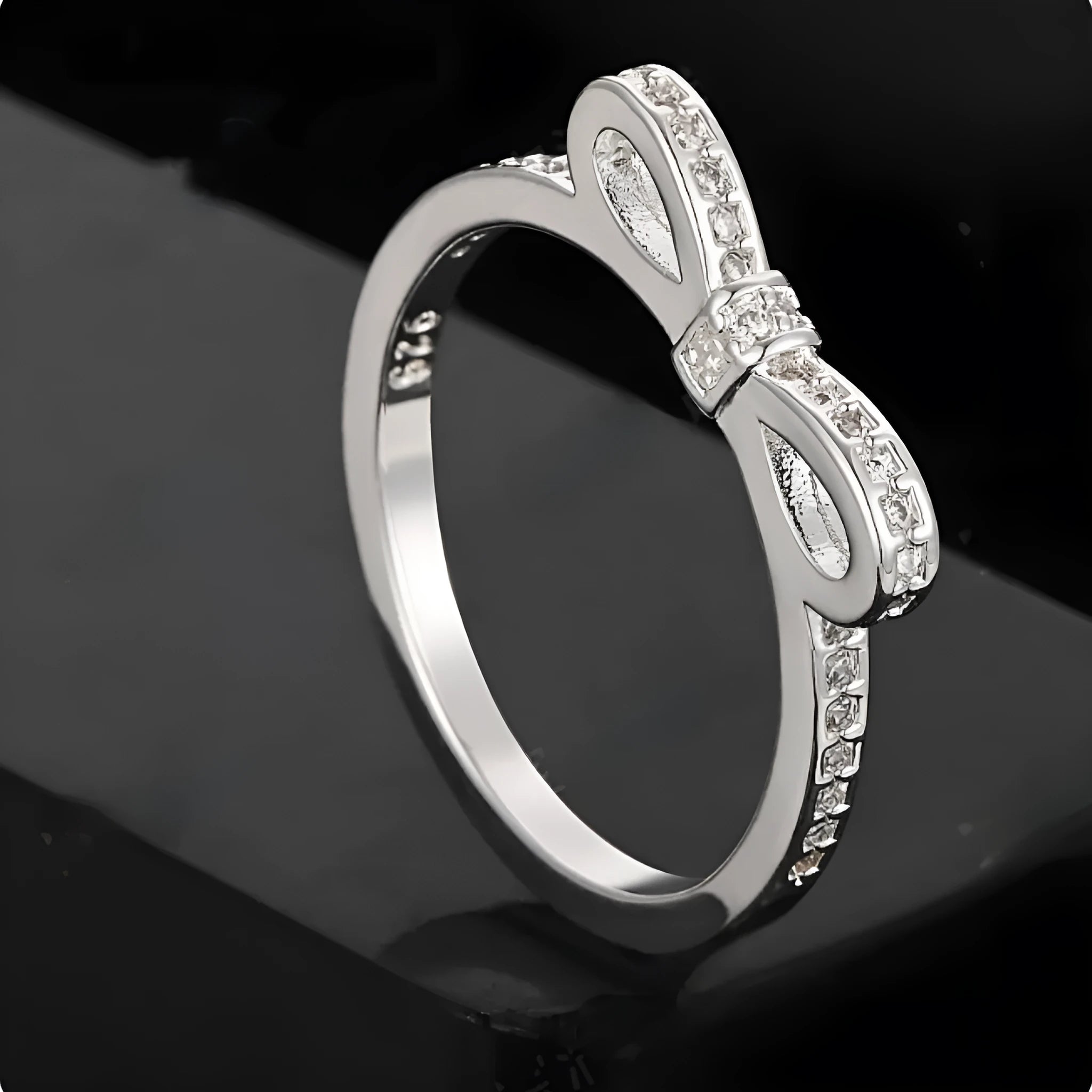 A silver couple-style ring with a bow shape decorated with rhinestones and zircon crystals.